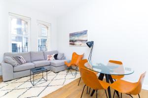 uma sala de estar com um sofá, uma mesa e cadeiras em Whitfield Street Apartments em Londres