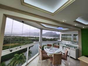 um quarto grande com uma mesa e cadeiras e janelas grandes em Apart Hotel Alecrim Praia de Camboinhas com Marina pe na areia em Niterói