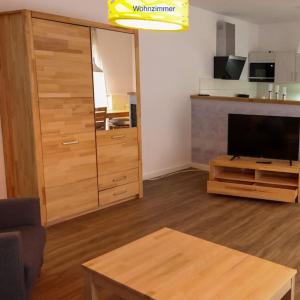 uma sala de estar com televisão e um centro de entretenimento em madeira em Freundliche Wohnung mit Parkplatz und Terrasse em Neubrandenburg