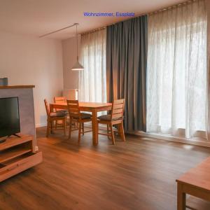 ein Esszimmer mit einem Tisch, Stühlen und einem TV in der Unterkunft Freundliche Wohnung mit Parkplatz und Terrasse in Neubrandenburg