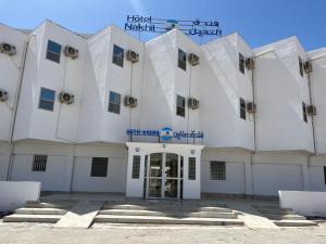ein weißes Gebäude mit einem Schild darüber in der Unterkunft HOTEL NAKHIL in Nouadhibou