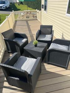 three wicker chairs and a table on a deck at Haven - Hafan Y Mor (Pwllheli) in Pwllheli