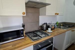 a kitchen with a stove top oven next to a microwave at Bury Stays in Bury