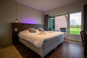 a bedroom with a large bed with a purple light at De Zeeuwse Tuinkamers in Kapelle