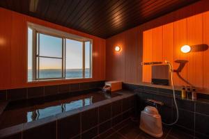 ein Bad mit einer großen Badewanne und einem Fenster in der Unterkunft BLUE LAGOON in Numazu