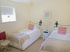 a bedroom with two beds and a chair and a window at Waterside in Warkworth