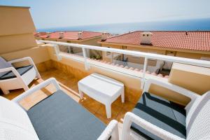 a balcony with chairs and a table and a view of the ocean at Residencial Playa de La Arena in Puerto de Santiago