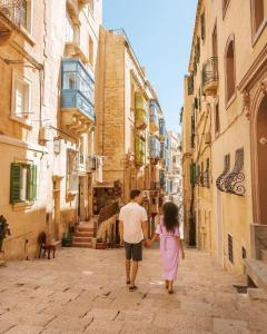 Ein Mann und ein kleines Mädchen laufen die Straße entlang in der Unterkunft Coast 52 Savynomad Harbour Residences wow Views in Valletta