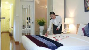 une femme dans une chambre d'hôtel à la recherche d'un lit dans l'établissement Mai Charming Hotel and Spa, à Hanoï