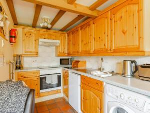 a kitchen with wooden cabinets and a white dishwasher at Pass the Keys The Stable in Norwich