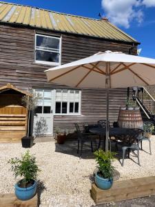 a patio with a table and an umbrella at The Queen Matilda Country Rooms in Tetbury