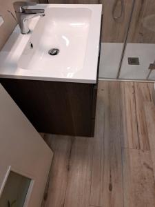 bagno con lavandino bianco e pavimento in legno di M. Szwed. Guest House old Bari a Bari