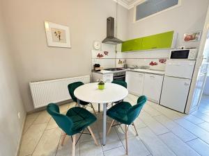 a kitchen with a white table and green chairs at ORANGEHOMES One Bedroom Cozy Apartment in Budapest