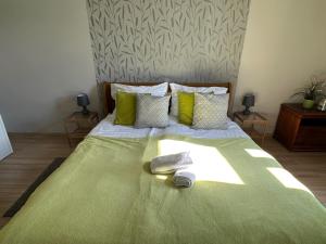 a bed with a green comforter and towels on it at ORANGEHOMES One Bedroom Cozy Apartment in Budapest