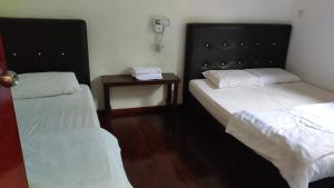 a room with two beds and a table with a phone at Happy Garden in Kampong Tenompok