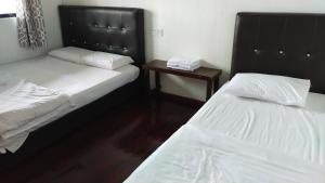 a bedroom with two beds and a night stand with a table at Happy Garden in Kampong Tenompok