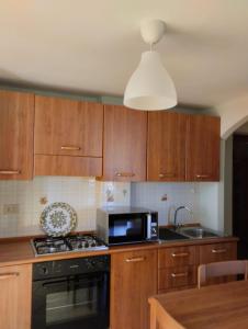 cocina con armarios de madera y microondas negro en franci e aurora house en Capo dʼOrlando