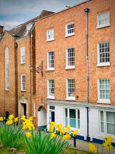a brick building with yellow flowers in front of it at Pass the Keys Superbly Located Handsome Georgian Townhouse in Shrewsbury