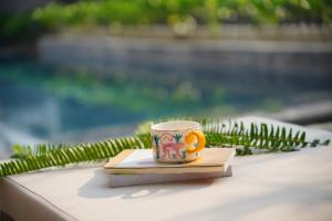 a coffee cup and a book on a table at Hola Villa 1 by Ovui in Hoi An