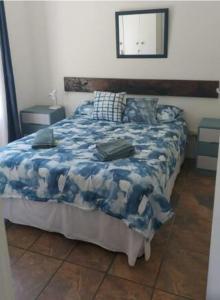 a bedroom with a bed with a blue blanket and a mirror at Streams Cottage in Bettyʼs Bay