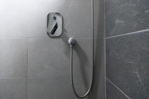 prysznic z wężem przymocowanym do ściany wyłożonej kafelkami w obiekcie Apartman Zelengora w mieście Tjentište