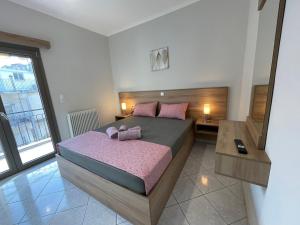 ein Schlafzimmer mit einem Bett mit rosa Kissen darauf in der Unterkunft Litsa's Apartment in Igoumenitsa
