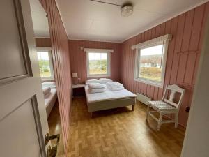 a bedroom with a bed and a chair and two windows at Summer house on Tjøme with beach and pier in Tjøme