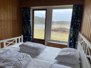 two beds in a room with a large window at Summer house on Tjøme with beach and pier in Tjøme