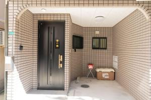 a brick hallway with a black door and a red chair at 悠の宿 in Osaka +27 photos
