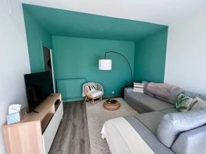 een woonkamer met een bank en een blauwe muur bij Casa Bert - Moderne & Design T2 - Centre Ville - Parking Gratuit in Brive-la-Gaillarde