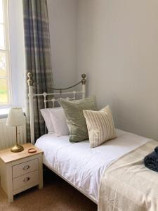 um quarto com uma cama e uma mesa com um candeeiro em Meldon Cottage in Morpeth, Northumberland em Morpeth