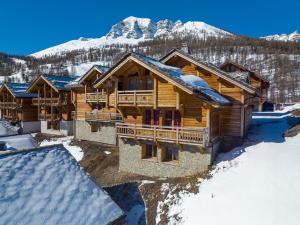 a log home in the snow with mountains in the background at Chalet Mountainside avec sauna et jacuzzi à 200m des pistes in Vars