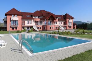 a swimming pool in front of a large house at Sanderson Apartments in Miercurea-Ciuc