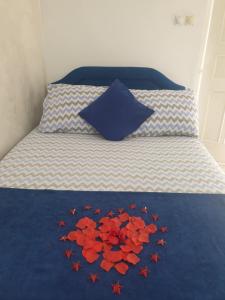 a bed with red flowers on a blue comforter at Savić Apartments in Kotor