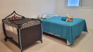 una cama con animales de peluche sentados en una manta azul en Praia Grande (12) - 3 quartos - 1 quadra Mar, en Torres