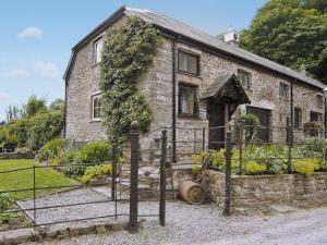 an old stone house with a gate in front of it at Gamekeepers Cottage - Hw7729 in Myddfai