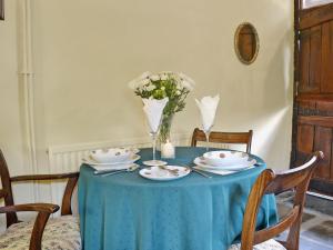 a blue table with plates and a vase of flowers at Gamekeepers Cottage - Hw7729 in Myddfai