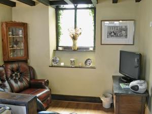 a living room with a leather chair and a television at Gamekeepers Cottage - Hw7729 in Myddfai