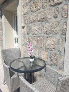 uma mesa de vidro com cadeiras e um vaso com flores em Savić Apartments em Kotor