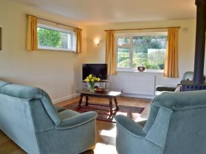 a living room with two chairs and a tv at Sandrock in Brighstone