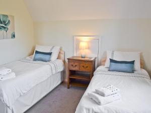 two twin beds in a room with a night stand at Sandrock in Brighstone