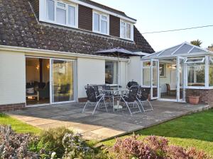 a patio with a table and chairs and an umbrella at Sandrock in Brighstone