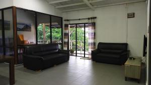 a living room with two black leather chairs and glass doors at Happy Garden in Kampong Tenompok