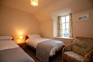 a bedroom with two beds and a chair and a window at Traditional Homely 2BD Cottage in Kemnay in Kemnay