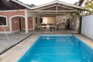 una piscina frente a una casa con mesa en Pousada Pérola do Guarujá Ltda- Me en Guarujá