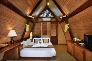 a bedroom with a bed in a room with wooden walls at Vila Ombak in Gili Trawangan