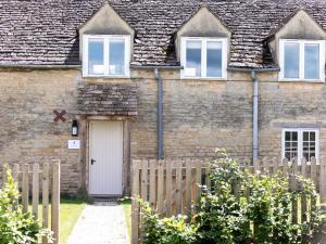 a brick house with a white door and a fence at The Long Barn in Ampney Crucis