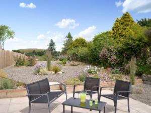 a patio with chairs and a table in a garden at River Cottage in Bladnoch