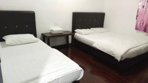 a room with two beds and a side table at Happy Garden in Kampong Tenompok