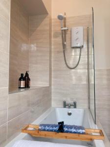 a bathroom with a bath tub with a shower at Meldon Cottage in Morpeth, Northumberland in Morpeth